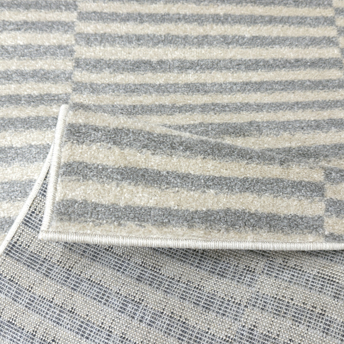 Cream and grey stripe rug folded back to show the backing