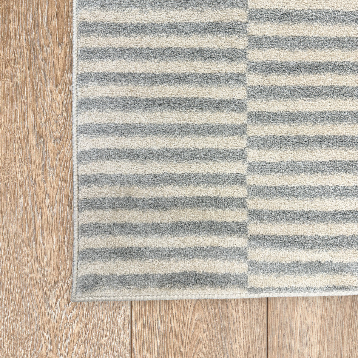 Corner of the cream and dark grey stripe rug on a light timber floor
