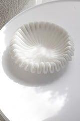 Large decorative wave bowl in soft white resin-sand blend on round table with sculptural light and shadows – minimalist modern style