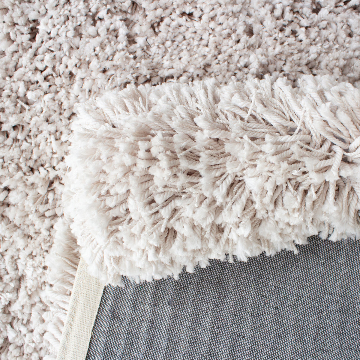 Folded corner showing the shaggy beige pile and the grey backing