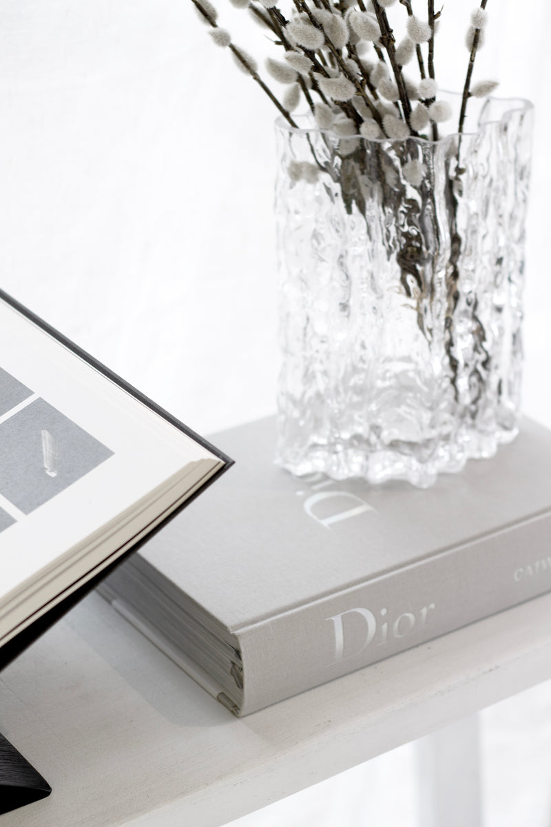 Dior Catwalk fashion book styled on a coffee table with flowers and modern decor.