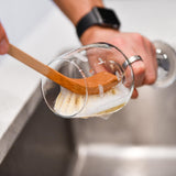 Wooden dish brush cleaning a plate at the kitchen sink, plastic free washing up