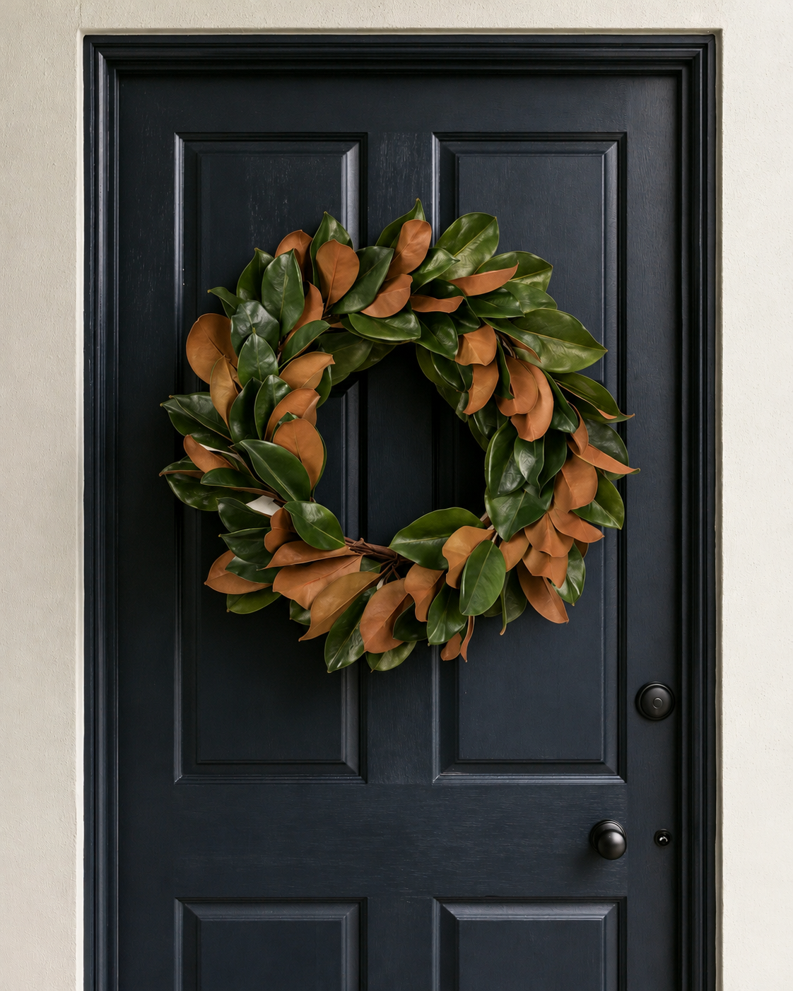 Magnolia Leaf Wreath with green and copper leaves hanging on a navy panelled front door