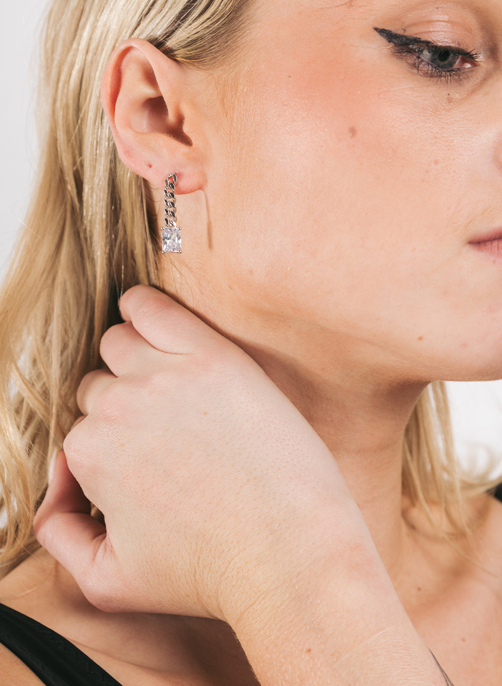 Close crop of the earring at the jaw, model touching her neck
