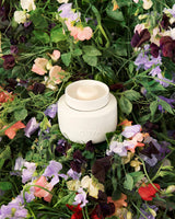 ECOYA Electric Wax Melter nestled within a bed of mixed garden florals and greenery, evoking the Sweet Pea & Jasmine Soy Wax Melt fragrance.