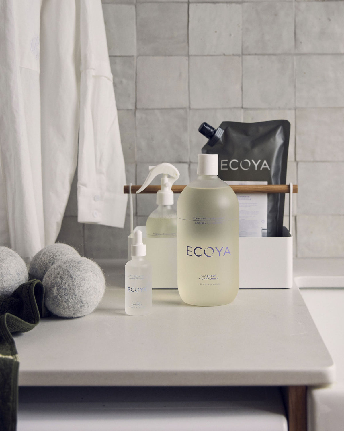 Laundry bench styled with Ecoya linen spray, laundry liquid, refill pouch, dryer balls and folded towels
