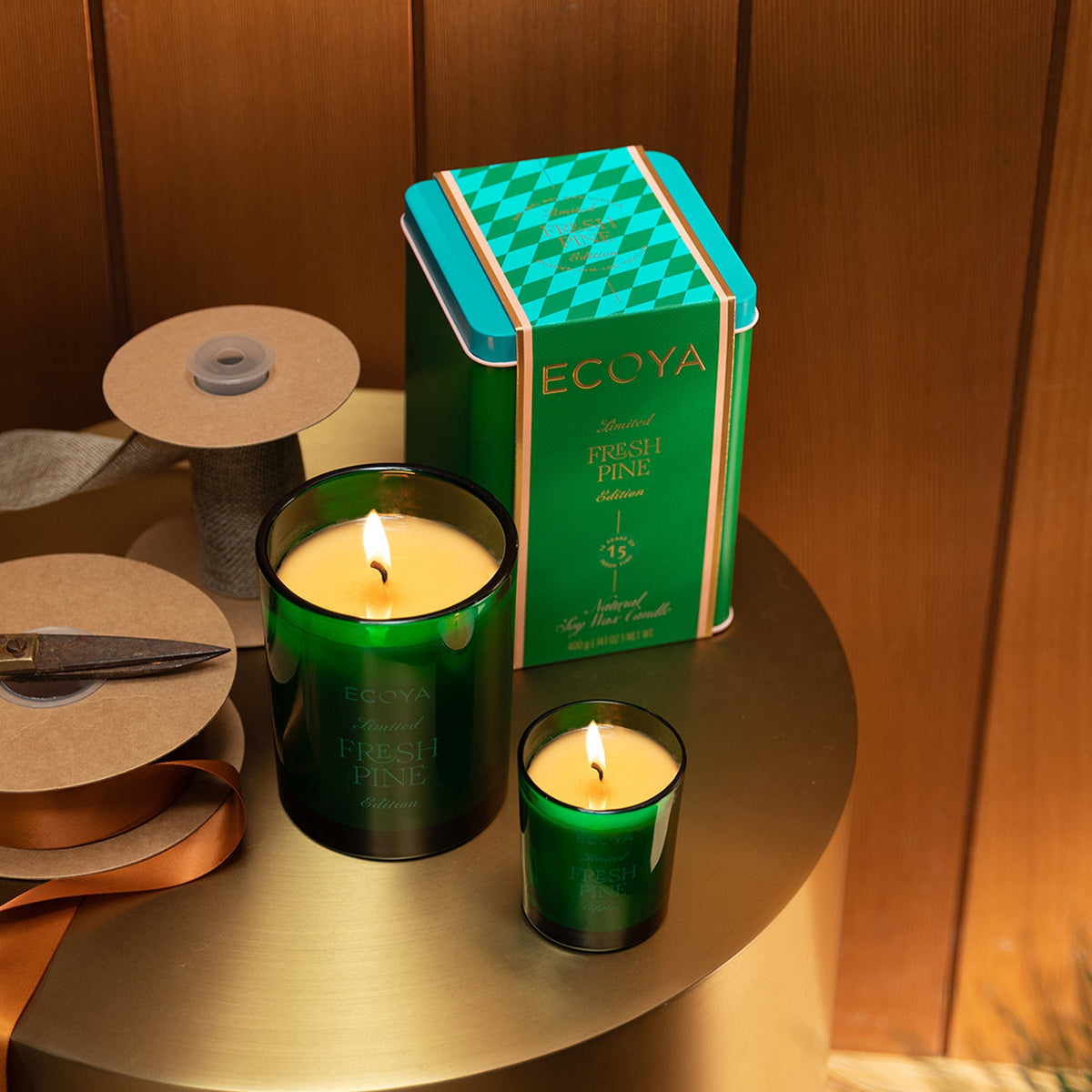 Lit Ecoya Fresh Pine mini and Madison candles on a round timber side table