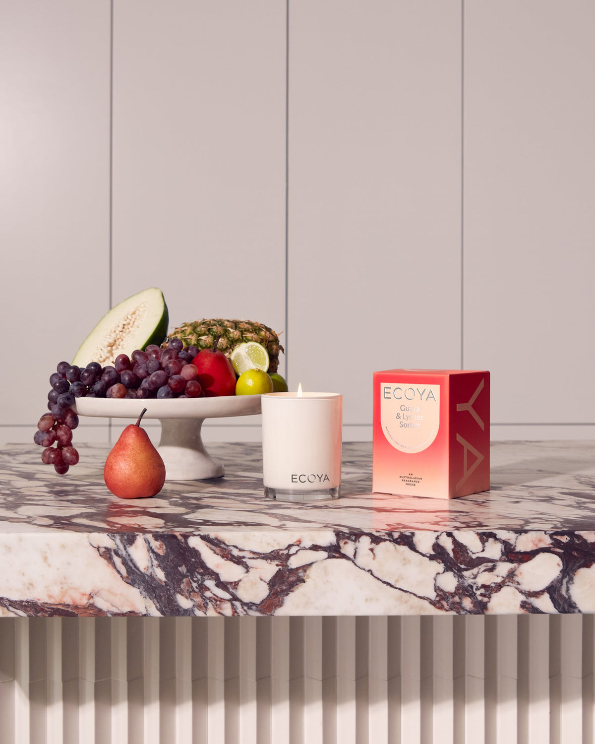 Ecoya Madison candle and gift box on a marble console with fruit against a panelled wall