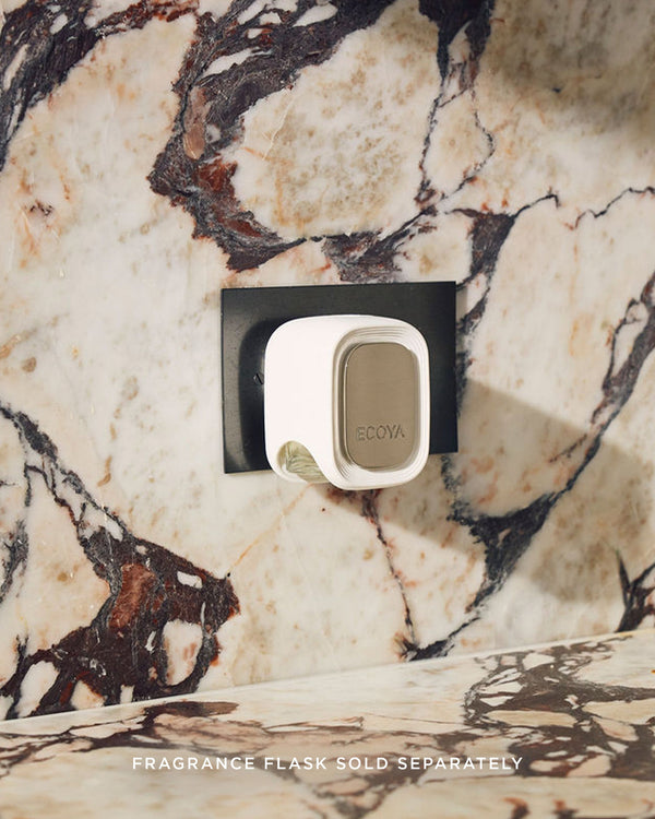 ECOYA Plug-In Diffuser plugged into a power socket on a marble wall, showing the sleek, modern design in use. Fragrance flask attachment sold separately