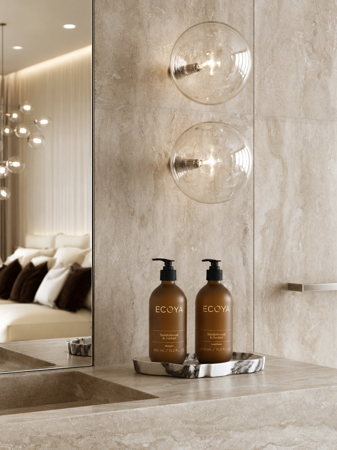 Ecoya Sandalwood & Amber shampoo and conditioner on a stone vanity in a warm, softly lit bathroom