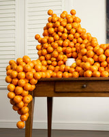 ECOYA Electric Wax Melter within a dramatic stacked mandarin and orange installation referencing the Mandarin Gin fragrance.