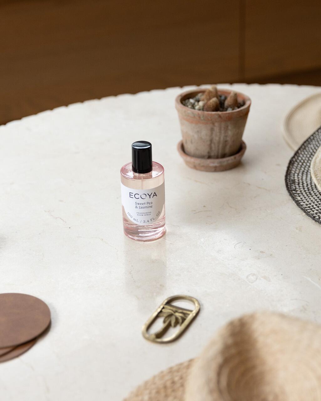 Ecoya Sweet Pea & Jasmine room spray in blush glass on a stone table with a cactus pot and straw hat