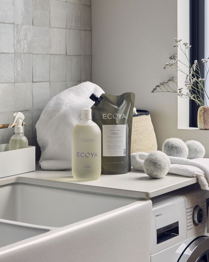 ECOYA wool dryer balls and fragrance dropper styled in a modern laundry with towels, detergent and soft natural light.