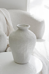 Eleni stone vase beside an armchair with soft white backdrop