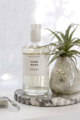 Calacatta marble petal-edge tray styled with Tasteology hand wash and a small glass vase with air plant