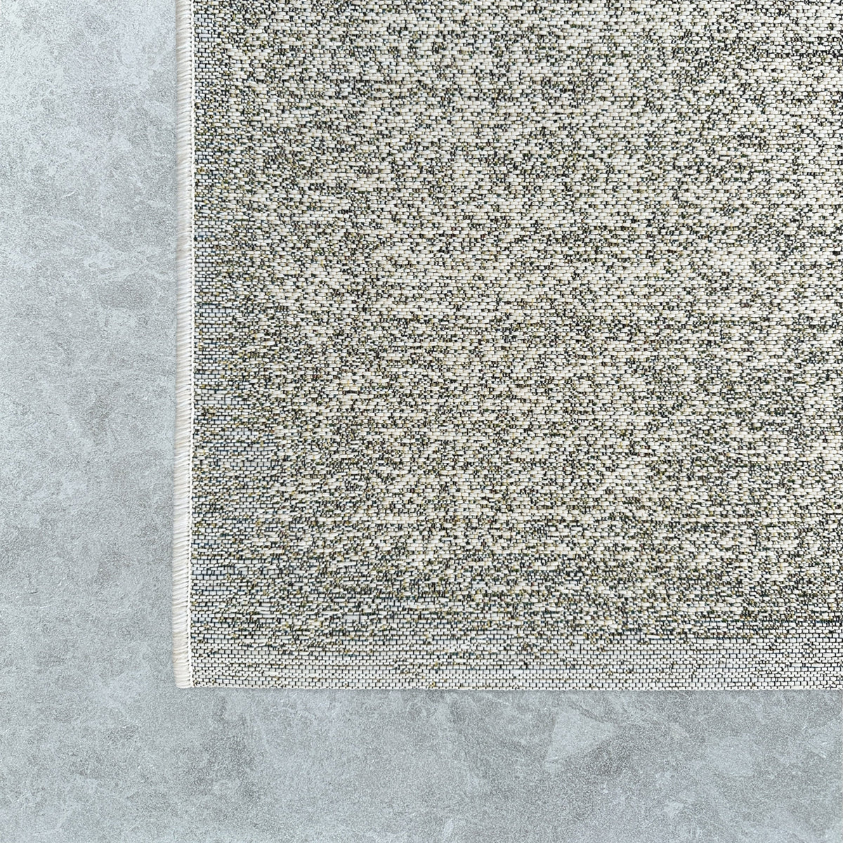 Corner of the flecked outdoor rug on pale stone pavers