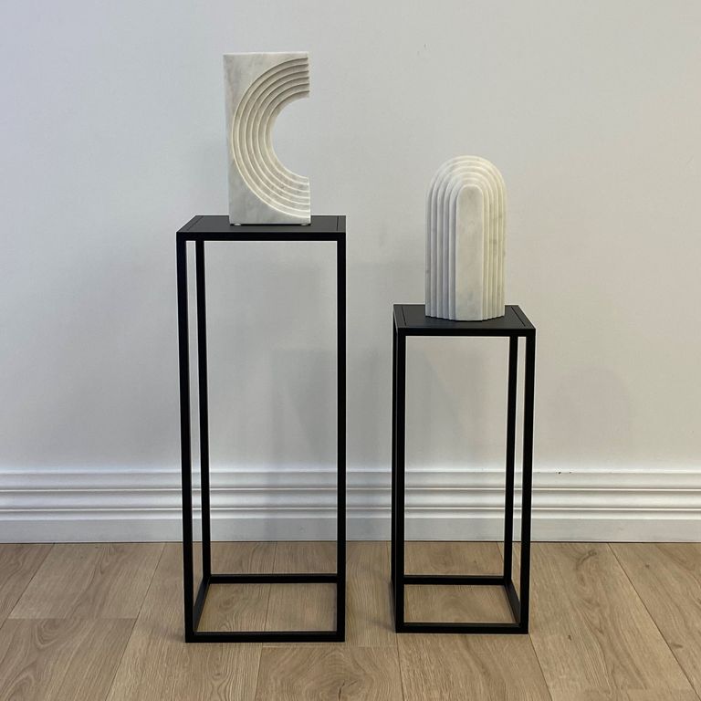 Plinths styled with a curved white sculpture and a ribbed vase on their tops