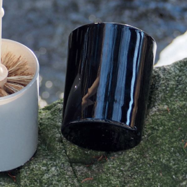 A black and white cup with Florence's GLASS TOILET BRUSH HOLDER - BLACK next to a watering can.
