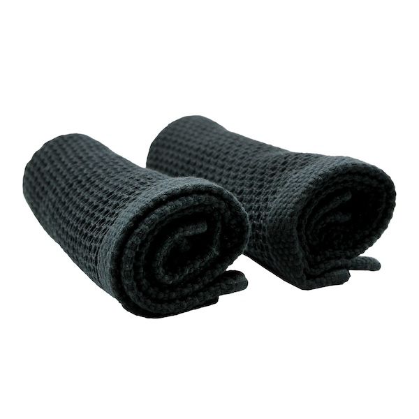 Two black cotton wash cloths rolled up, on white
