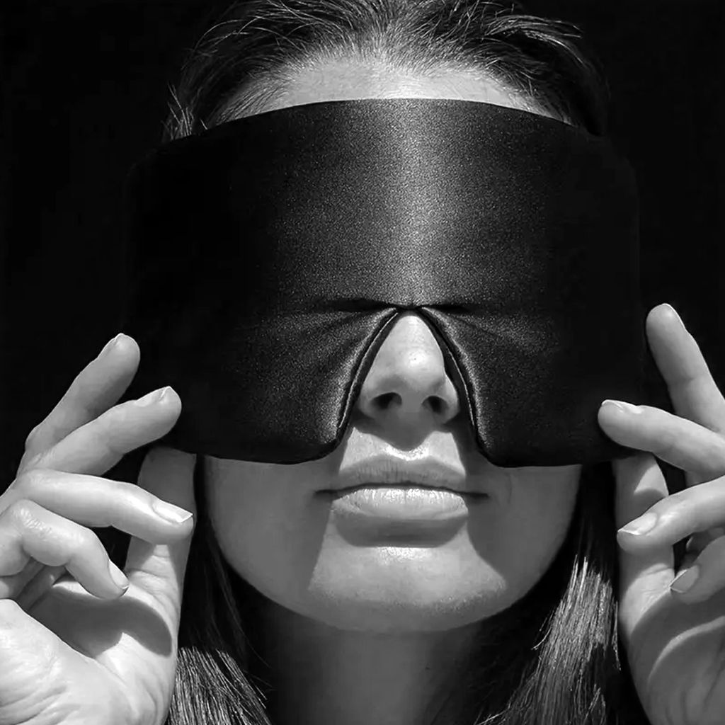 Woman wearing the black mulberry silk eye mask, hands resting at her temples