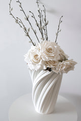 White faux rose bouquet with pussy willow stems styled in a sculptural white vase on a neutral table