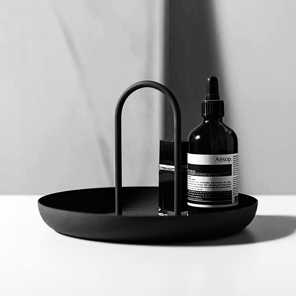 Black FIKA tray styled on a bench with a dark glass dropper bottle and a small glass vessel