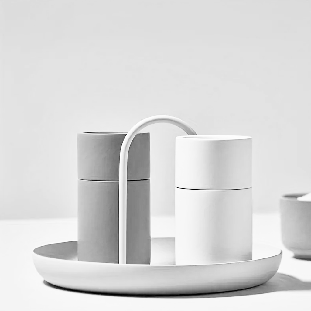 White FIKA tray holding two cylindrical grinders on a pale worktop, arched handle rising between them