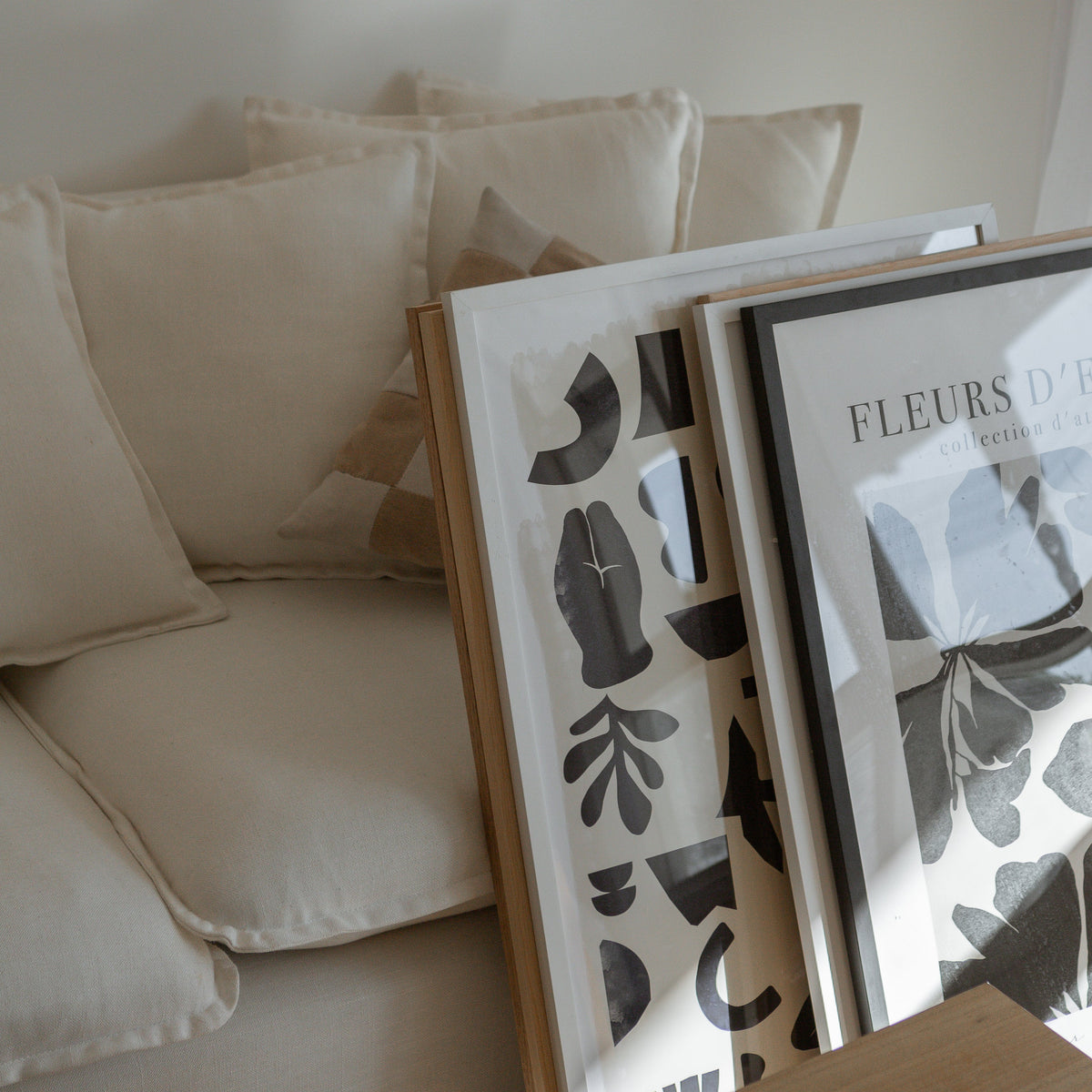 Fleurs d'Encre print in a natural frame leaning with other prints beside a cream armchair
