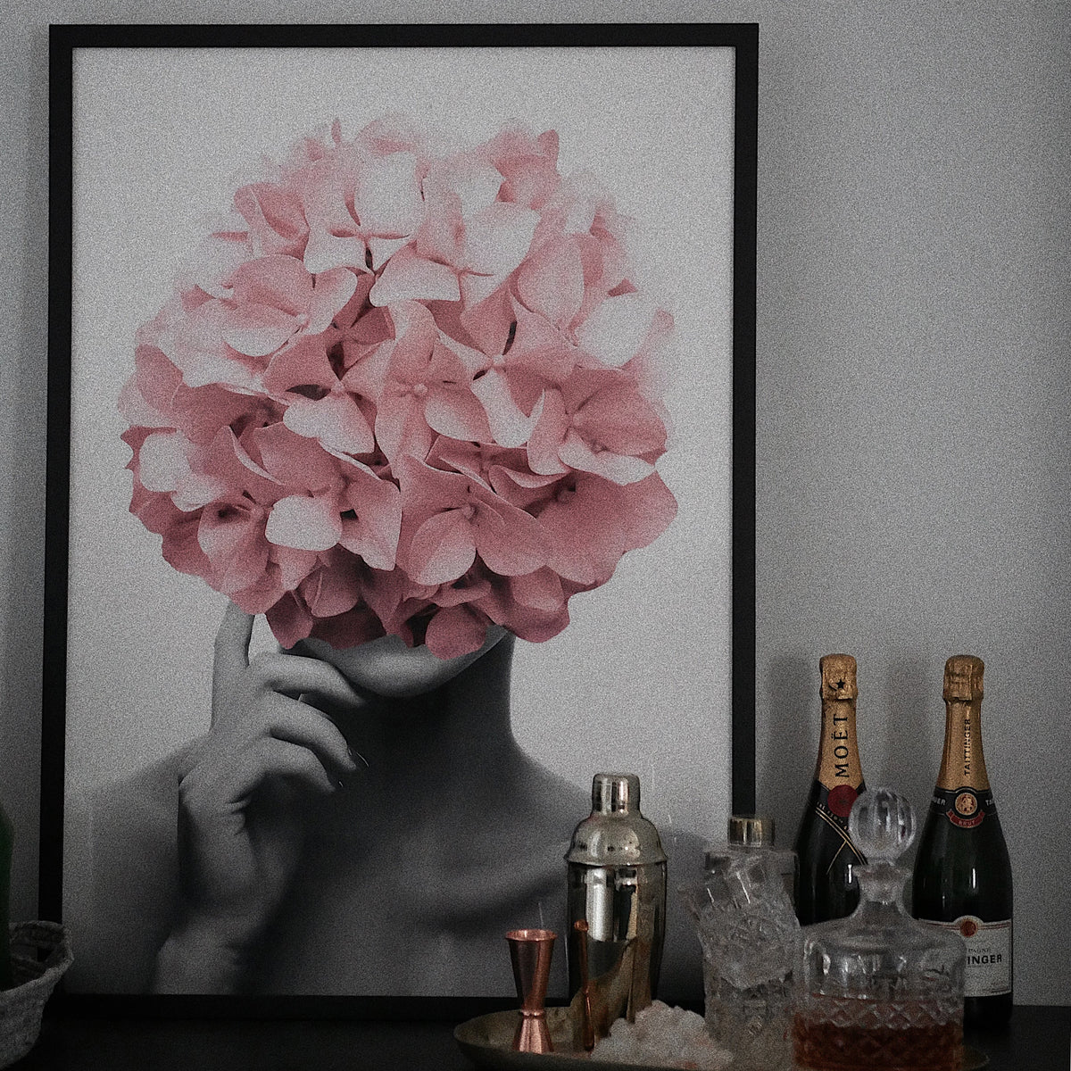 Flower Bomb print in a black frame on a bar cart beside champagne bottles