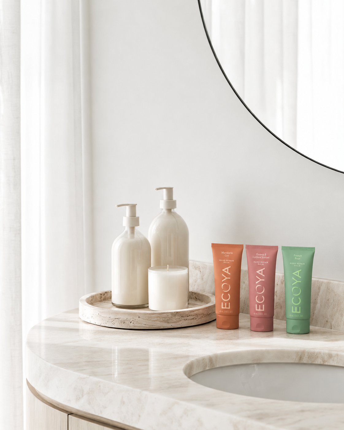 Ecoya Hand Repair Trio tubes standing on a marble vanity beside a tray of pump bottles