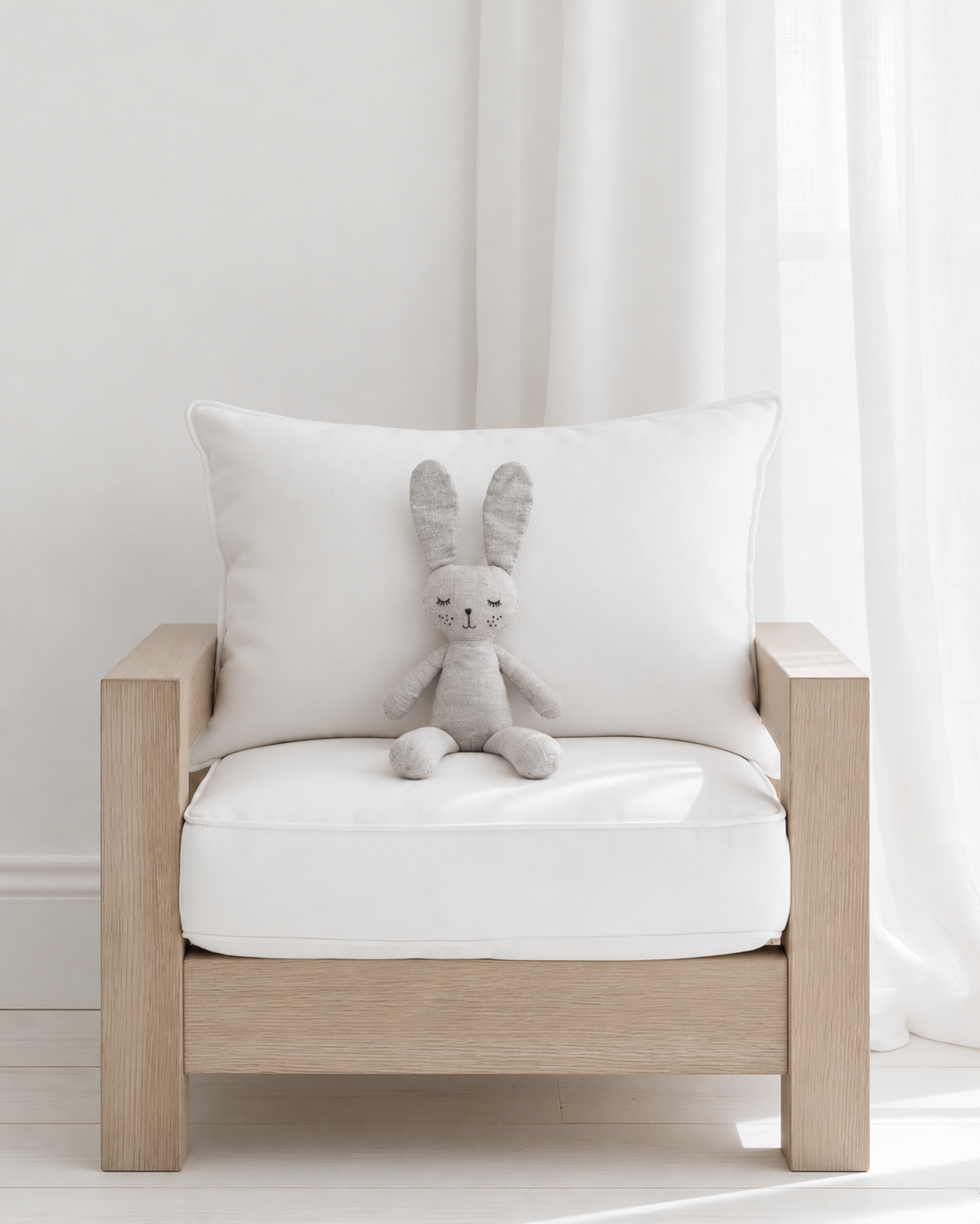 Grey the Bunny soft toy by Lily & George sitting on a mini oak armchair