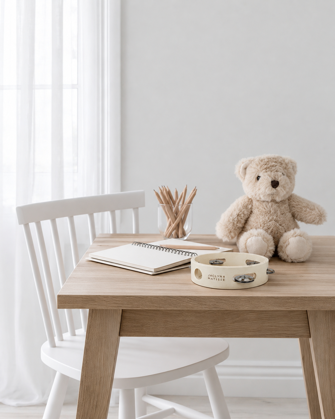 Jaclyn & Matisse white wooden tambourine on a child's oak desk beside a fawn teddy bear