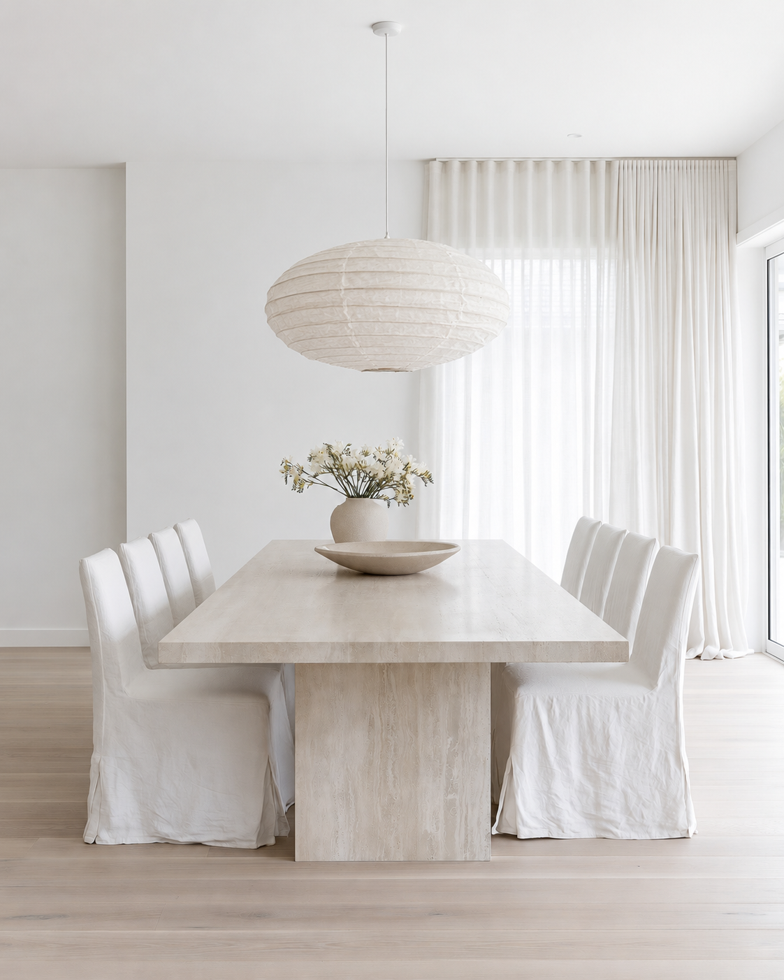 Oval Linen Pendant Light Shade 60cm in white hanging over a travertine dining table with linen slipcovered chairs