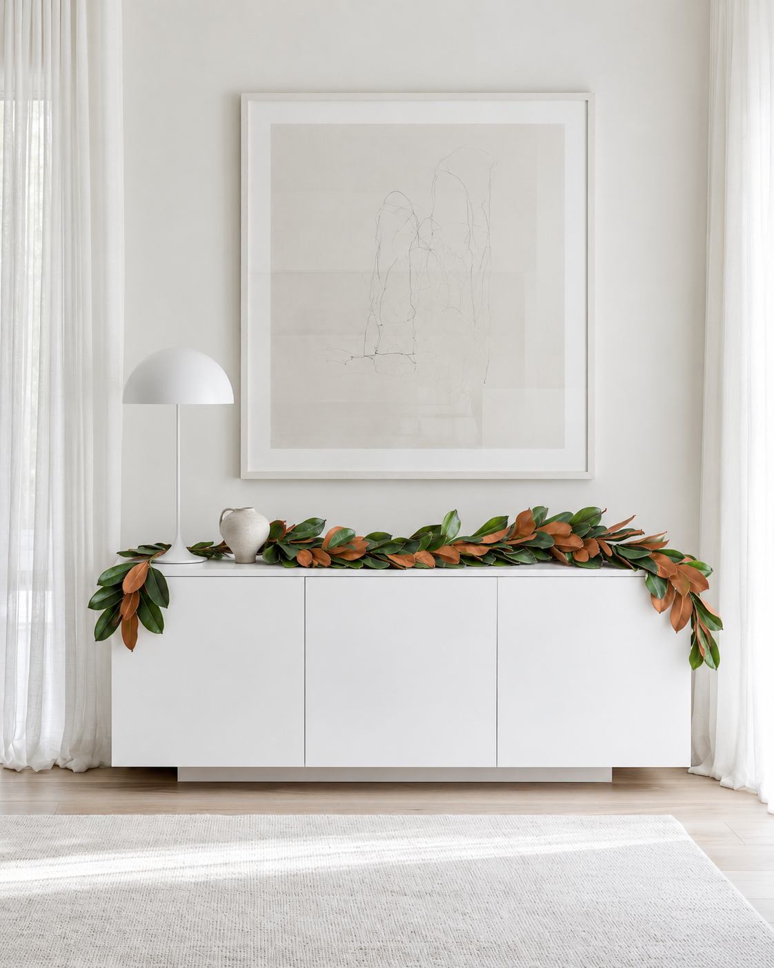 Magnolia leaf garland laid along a white sideboard with its ends trailing over the sides