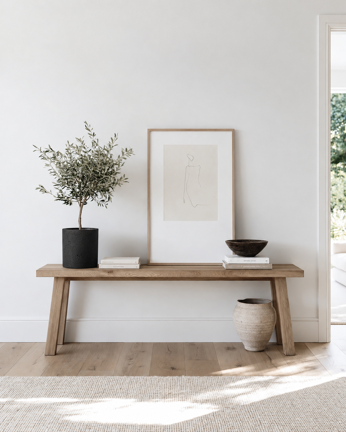 Large black concrete pot holding a small olive tree on an oak bench console