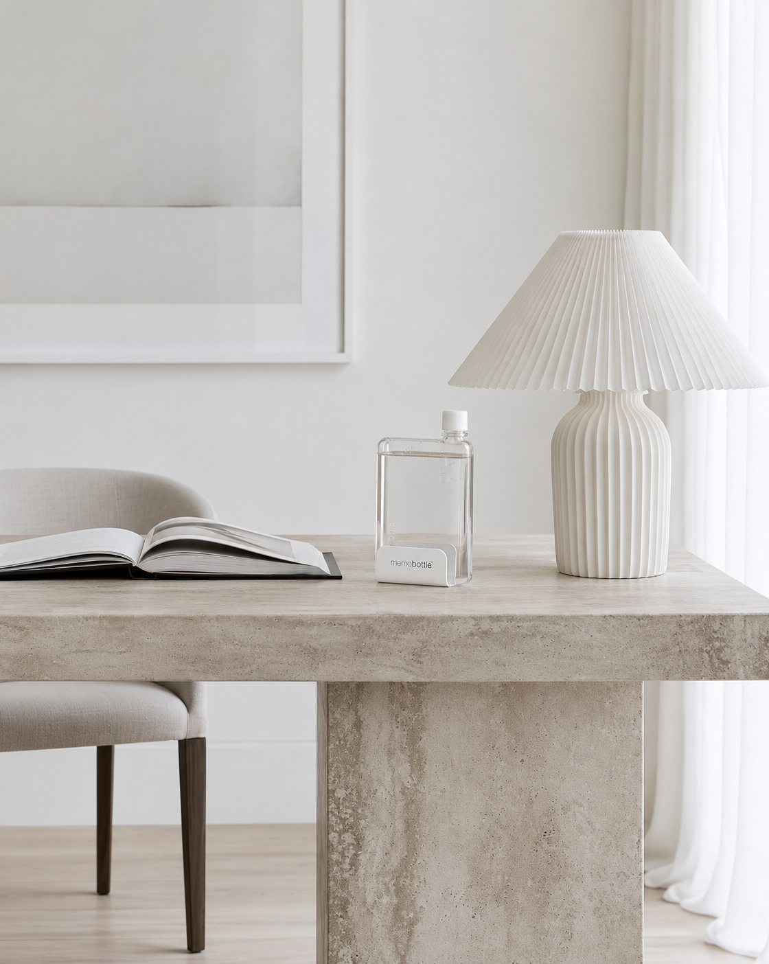 Universal Desk Stand on a desk holding a clear flat A5 water bottle full of water, beside a lamp