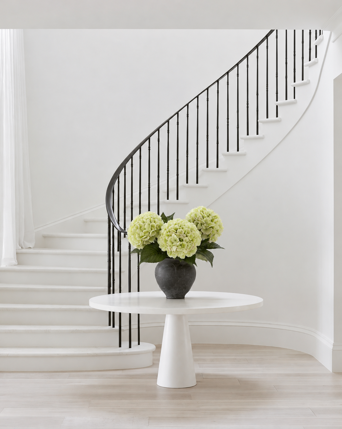 Three Dutch Green Hydrangea stems in the black vase on the round pedestal table