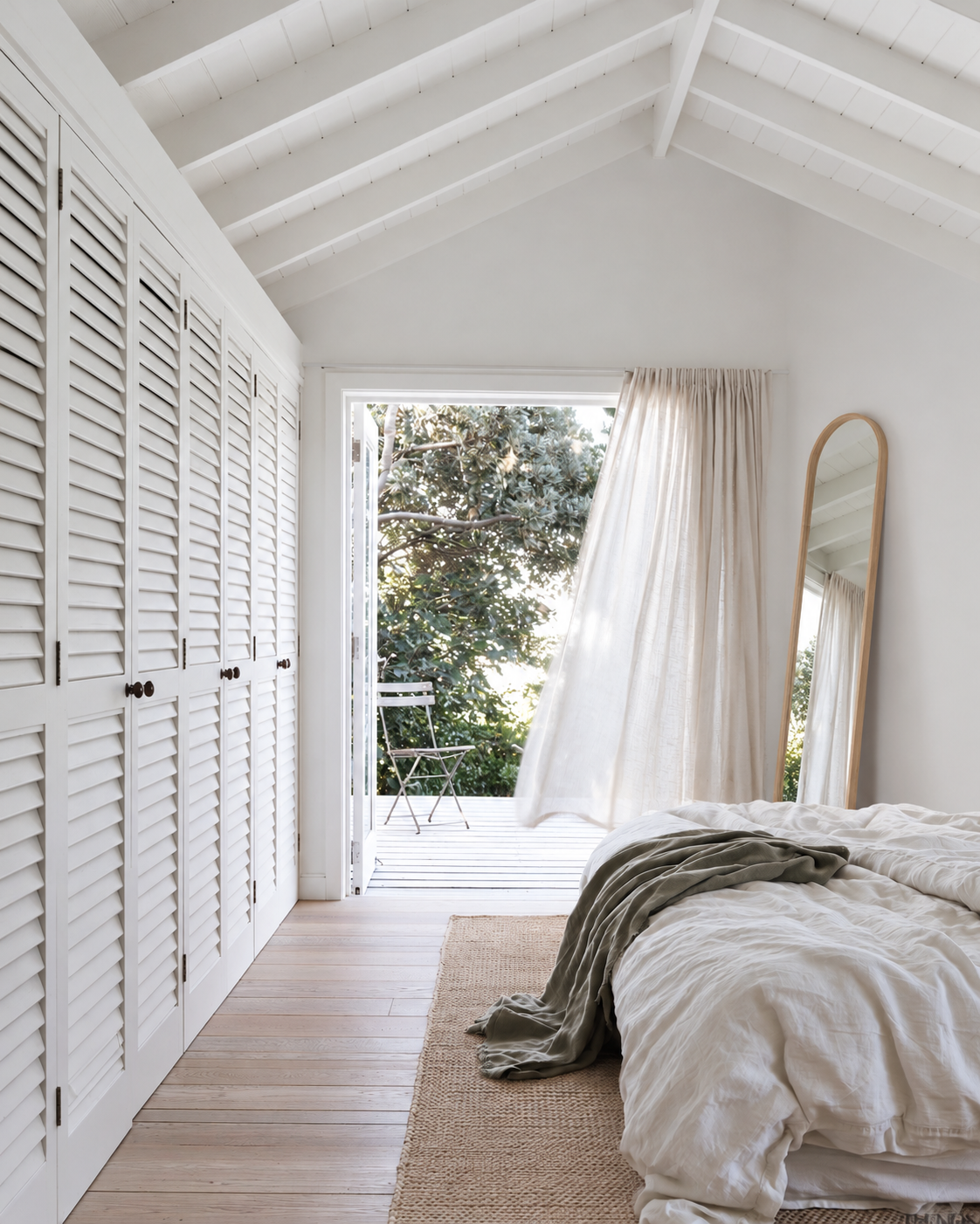 Natural Bellwood leaning mirror beside French doors in a bedroom