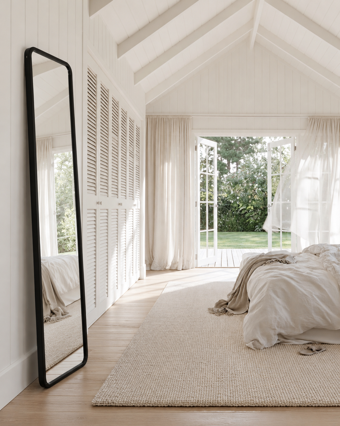 Umbra Hub leaning mirror in black styled leaning in a vaulted bedroom with no other mirror
