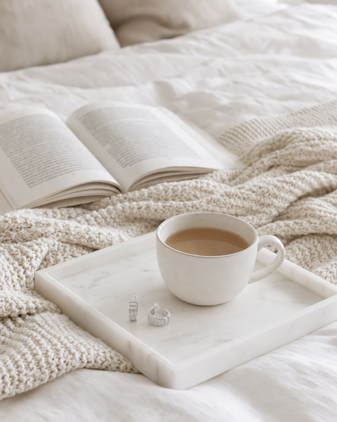 Federation Impressions Earrings in silver with clear crystals in a white marble tray on a linen bed beside a cup of tea