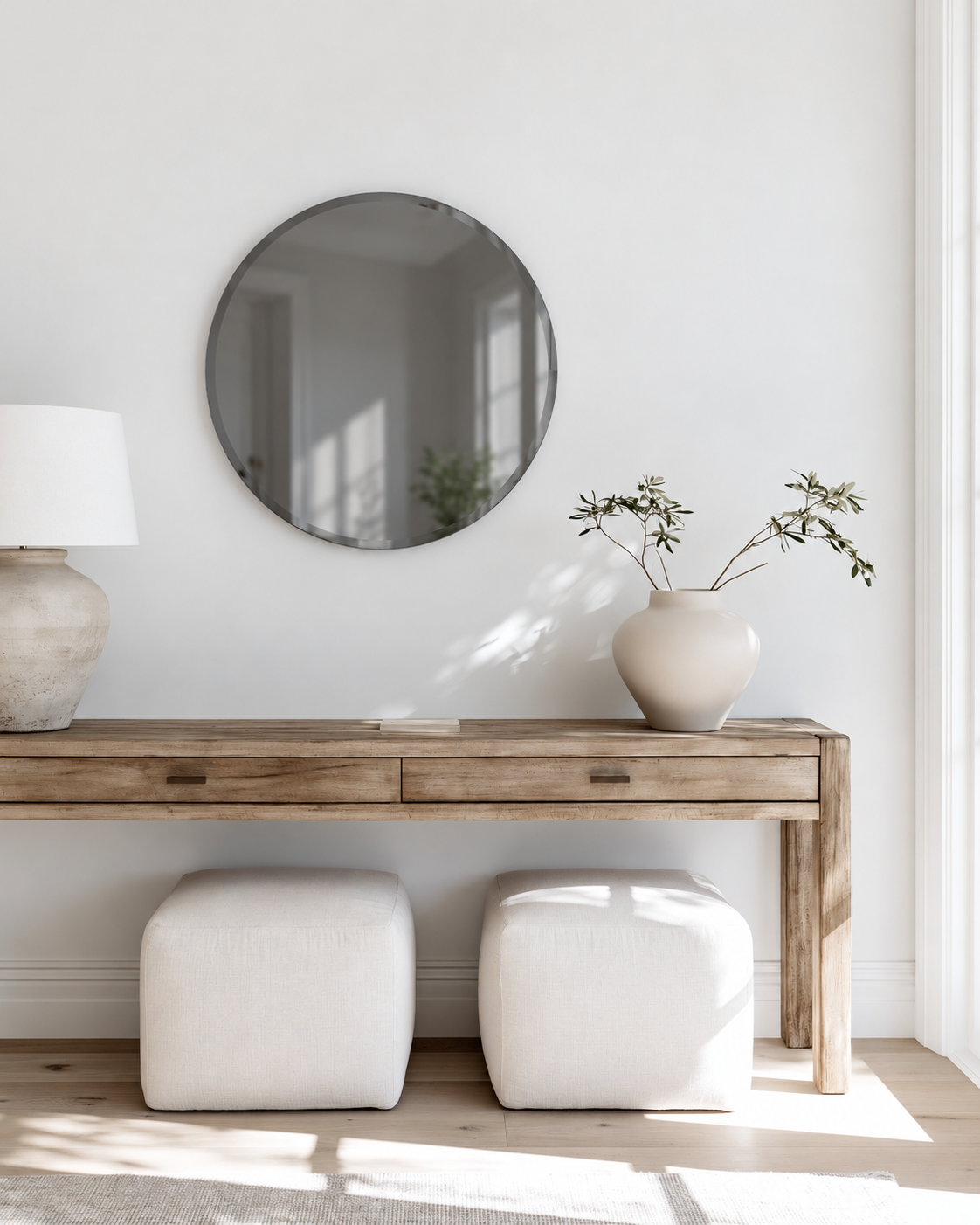 Umbra Bevy round smoke mirror above a timber console with two cream stools