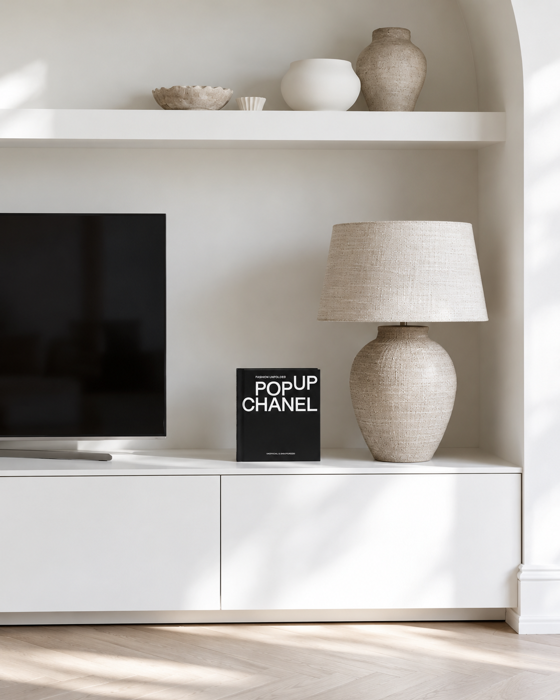 Fashion Unfolded: Pop-Up Chanel standing on a white media console beside a linen lamp