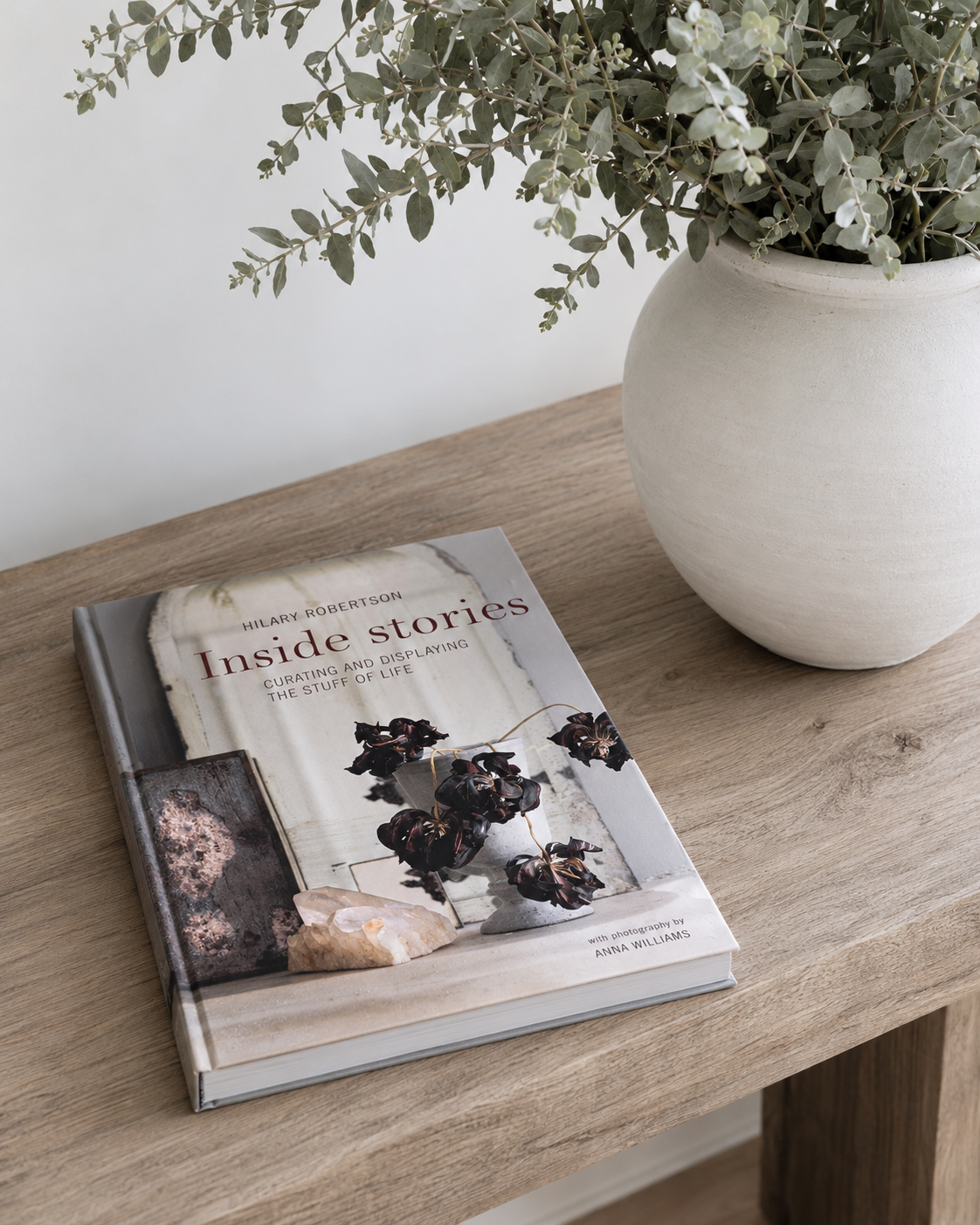 Inside Stories by Hilary Robertson on a timber console beside a vase of eucalyptus
