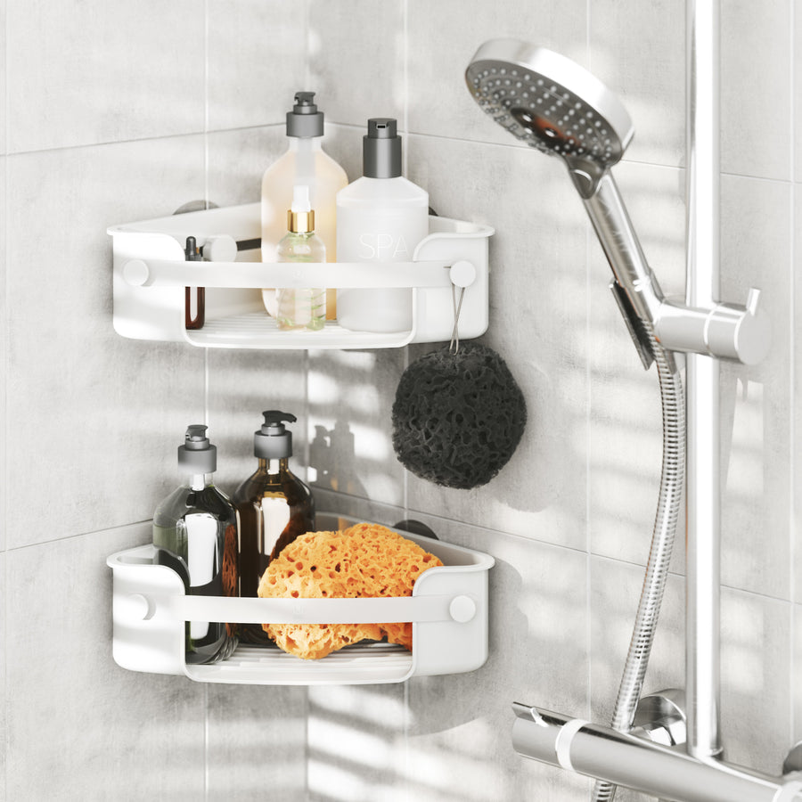 Two Umbra Flex corner bins in white in a tiled shower with bottles and a sponge