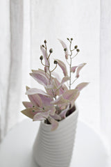 Garden sage faux foliage spray with soft green and blush pink leaves, styled in a tall white ribbed vase in front of sheer curtains for minimal neutral home decor