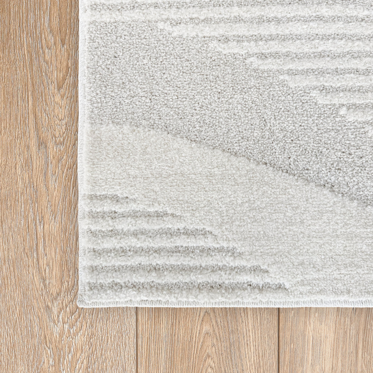 Corner of the cloud white rug on a timber floor showing the wave pattern