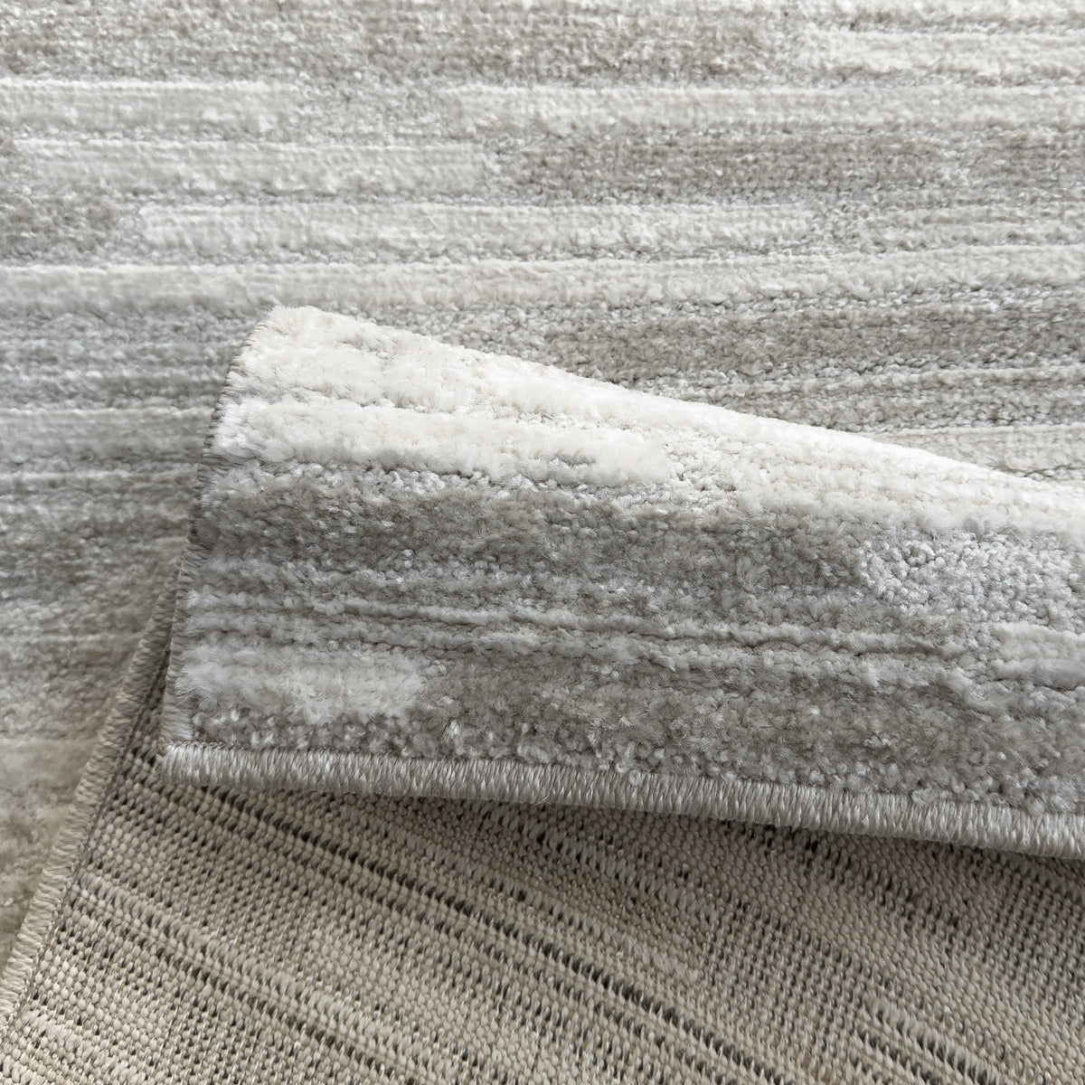 Folded corner showing the beige streaked pile and the woven backing