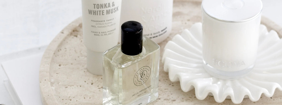 White ruffle ceramic tray with lotion, perfume and a candle on a travertine surface