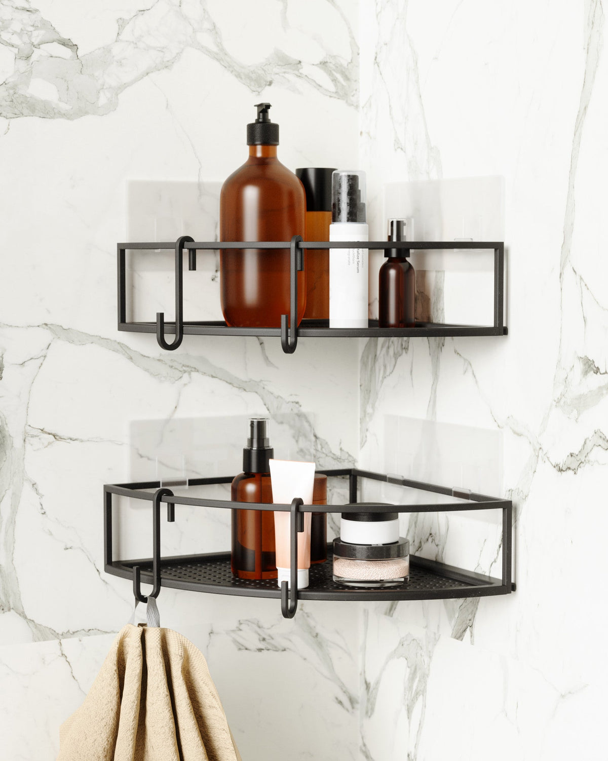 Two Umbra Cubiko corner bins in black on marble tiles with a towel on the hook