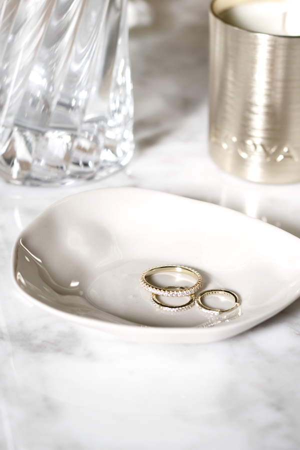 Sterling silver zirconia eternity band styled in a ceramic dish on marble with candle and crystal vase.